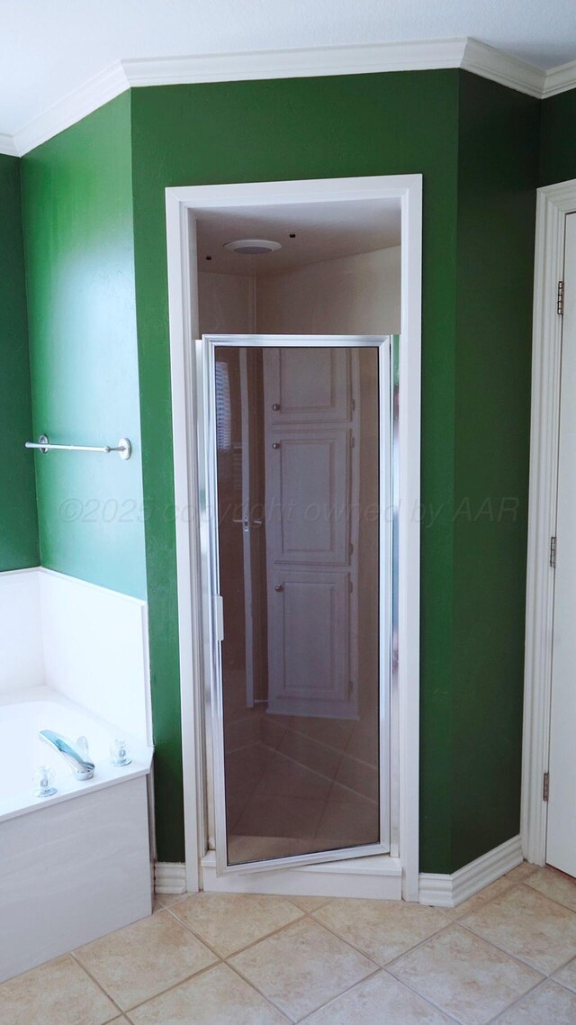 bathroom with baseboards, tile patterned flooring, a shower stall, a garden tub, and ornamental molding