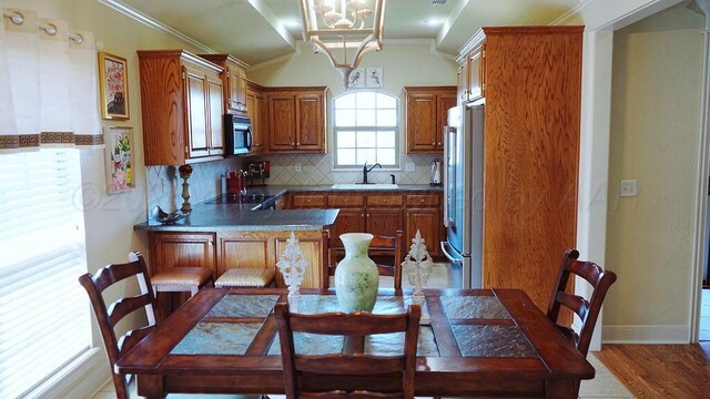 kitchen with high quality fridge, ornamental molding, a sink, light wood-style floors, and tasteful backsplash