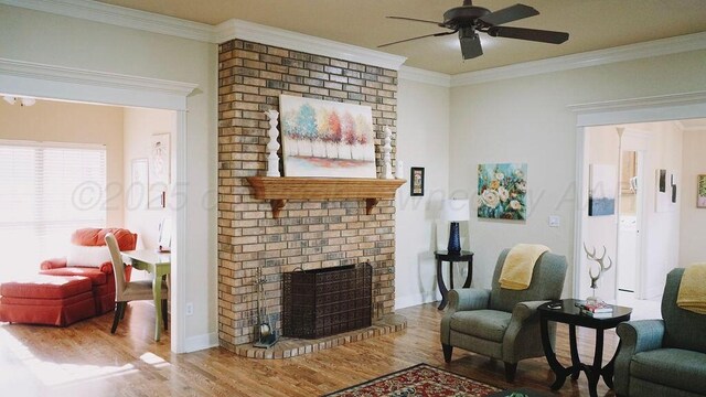 living area with a ceiling fan, wood finished floors, a fireplace, and crown molding