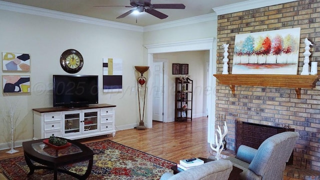 living area featuring baseboards, a ceiling fan, wood finished floors, a brick fireplace, and crown molding