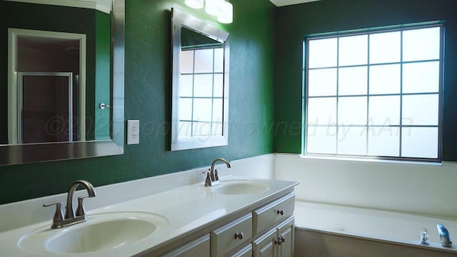 bathroom with a textured wall, a garden tub, a sink, and double vanity