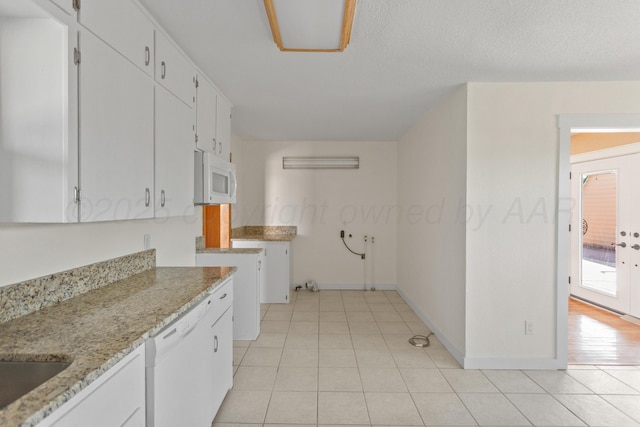 kitchen featuring white appliances, light tile patterned floors, baseboards, light stone counters, and white cabinetry