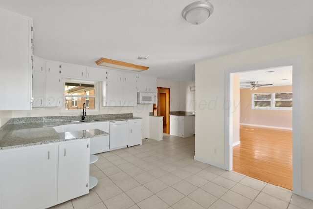 kitchen featuring white appliances, plenty of natural light, light stone countertops, white cabinetry, and a sink