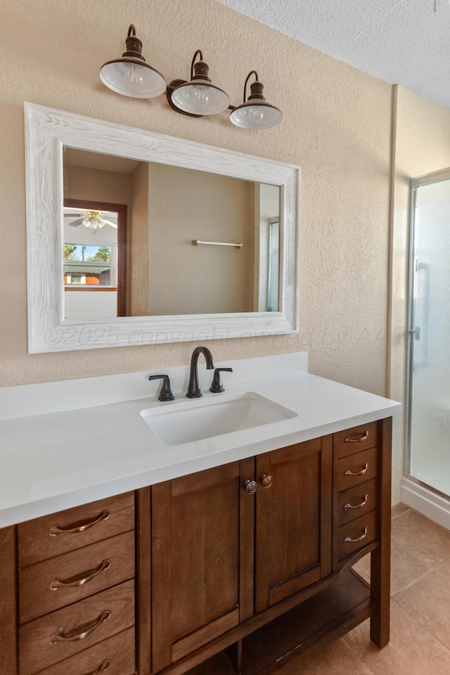 bathroom with a textured ceiling, a textured wall, vanity, a shower stall, and tile patterned floors