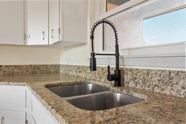 details with stone counters, a sink, and white cabinets