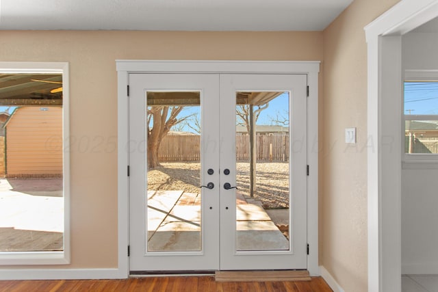 doorway featuring baseboards, wood finished floors, and french doors