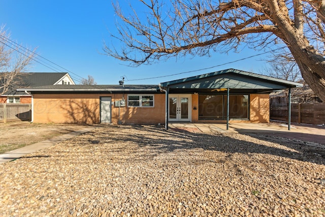 view of front of home with french doors, a patio area, fence, and brick siding