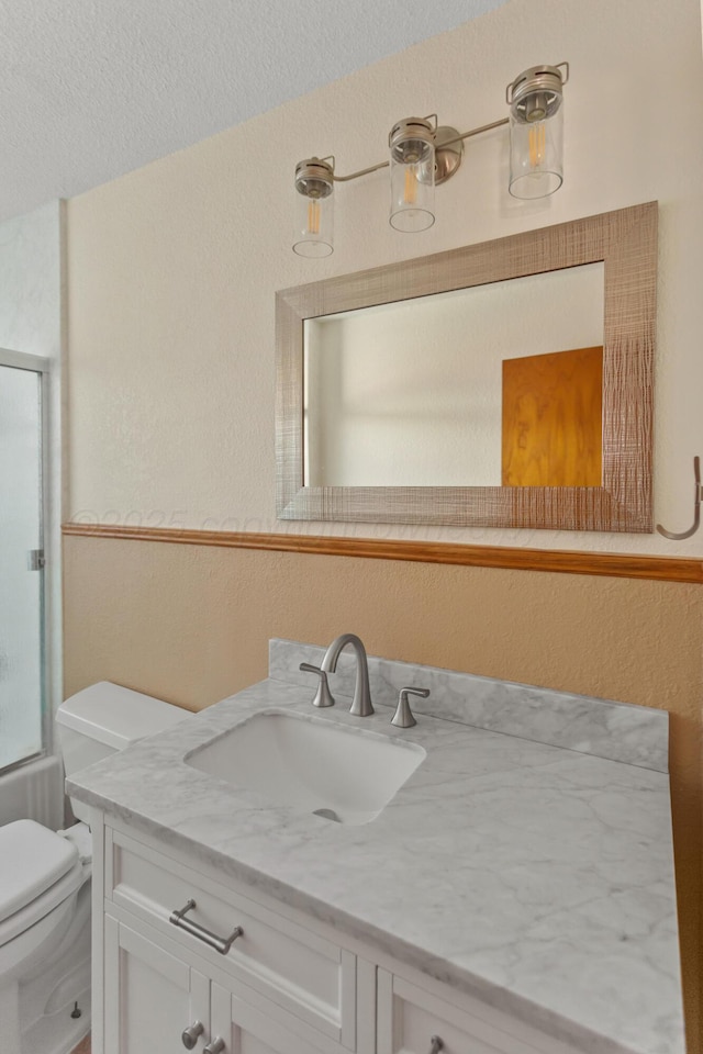 full bath with enclosed tub / shower combo, vanity, toilet, and a textured ceiling