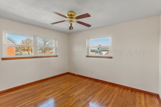 empty room with plenty of natural light, baseboards, and wood finished floors