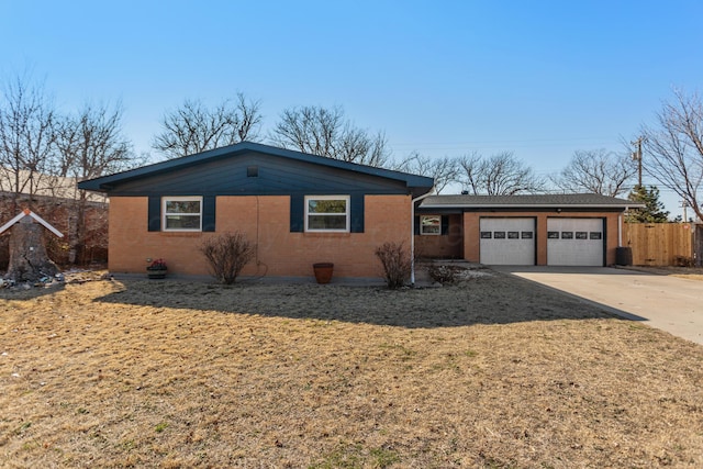 single story home with a garage, concrete driveway, brick siding, and a front lawn