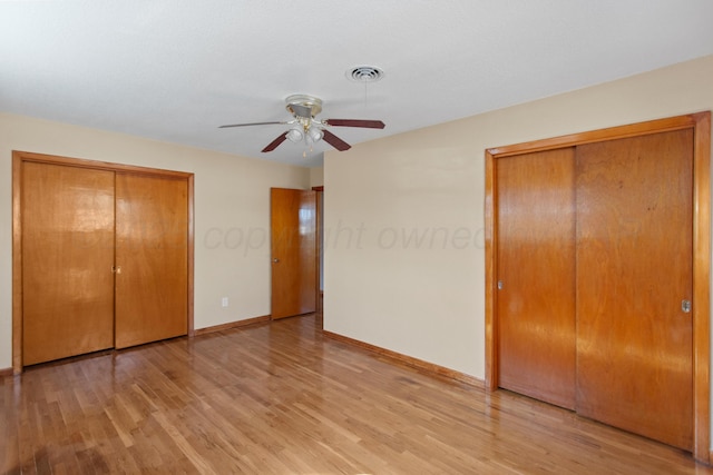 unfurnished bedroom featuring light wood finished floors, multiple closets, visible vents, and baseboards