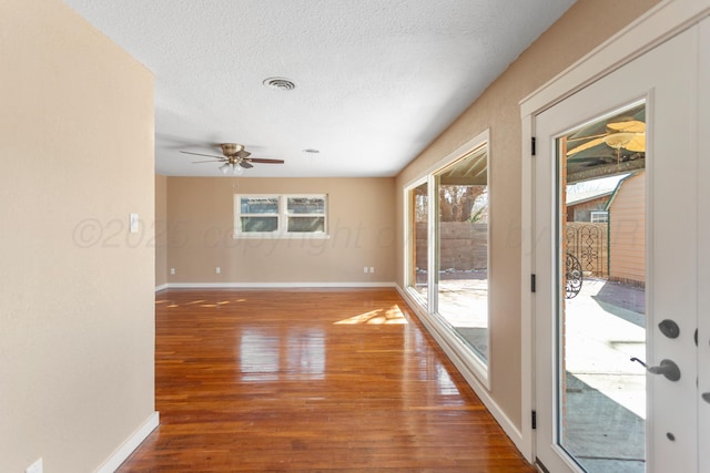 spare room featuring visible vents, a textured ceiling, baseboards, and wood finished floors