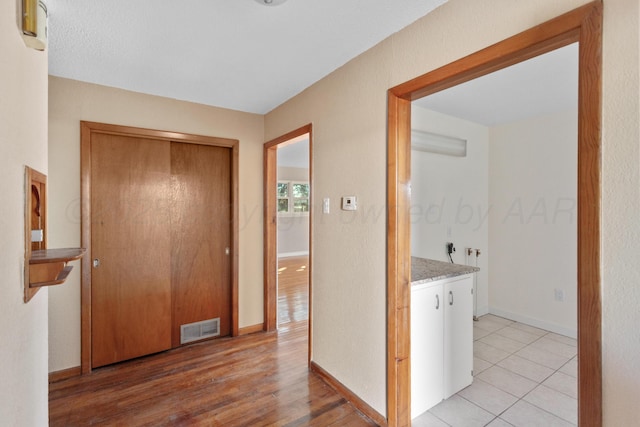 hallway featuring baseboards, visible vents, and light wood-style floors