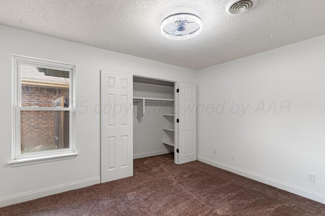 2607 15th Ave, Canyon, TX 79015 - unfurnished bedroom featuring dark carpet, a textured ceiling, baseboards, a spacious closet, and a closet