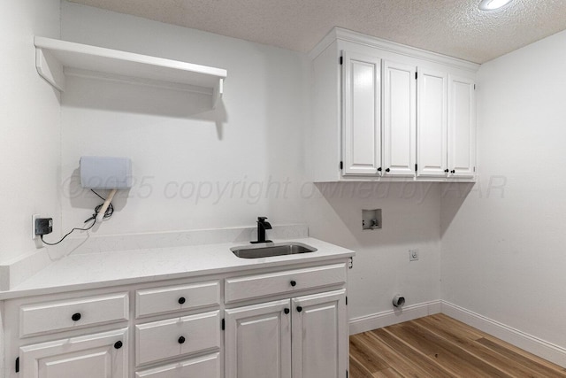 2607 15th Ave, Canyon, TX 79015 - clothes washing area featuring washer hookup, cabinet space, wood finished floors, a textured ceiling, and baseboards