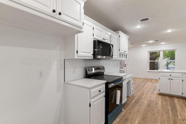 2607 15th Ave, Canyon, TX 79015 - kitchen with stainless steel microwave, electric stove, a textured ceiling, light countertops, and decorative backsplash