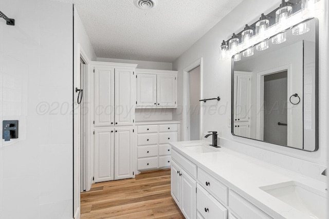 2607 15th Ave, Canyon, TX 79015 - bathroom featuring wood finished floors, a textured ceiling, and double vanity