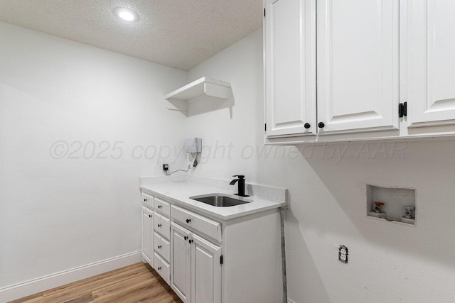 2607 15th Ave, Canyon, TX 79015 - laundry room featuring washer hookup, cabinet space, baseboards, light wood-type flooring, and a textured ceiling