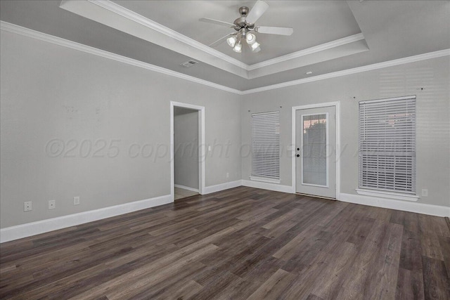 empty room featuring dark wood-type flooring, a tray ceiling, crown molding, baseboards, and ceiling fan