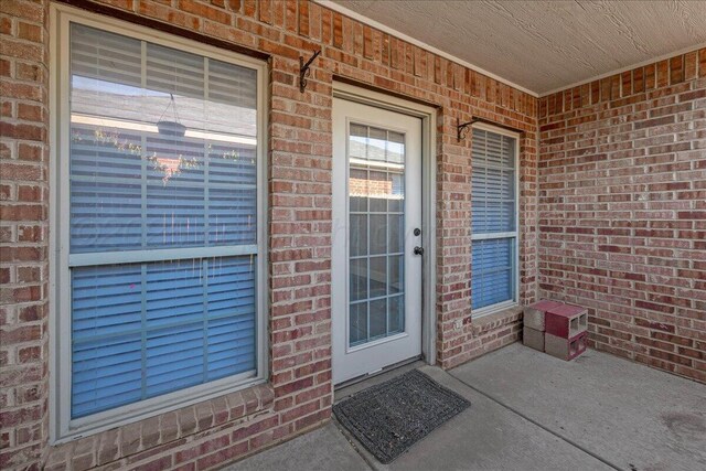 doorway to property featuring brick siding and a porch