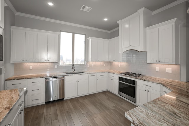 kitchen featuring stainless steel appliances, white cabinetry, sink, and crown molding