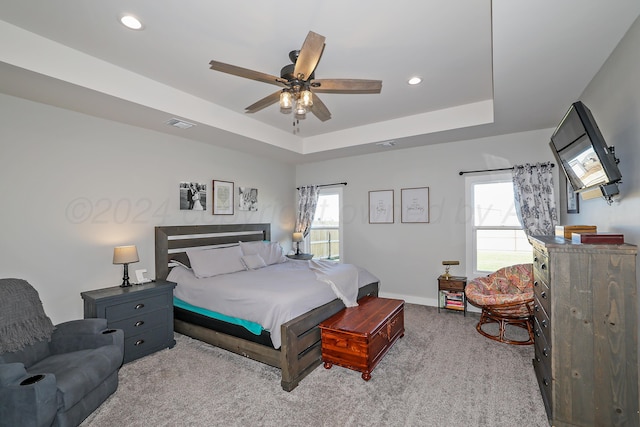 bedroom with ceiling fan, a raised ceiling, and light carpet