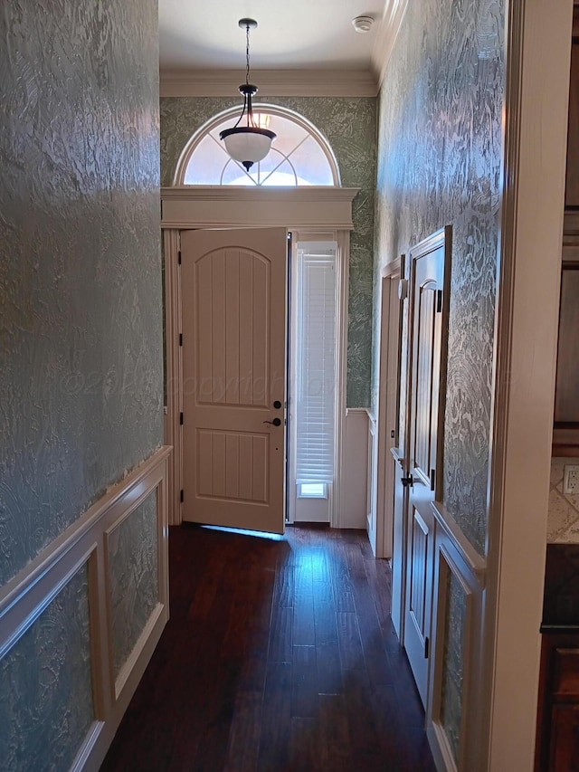 entrance foyer with a wainscoted wall, wallpapered walls, wood-type flooring, and crown molding