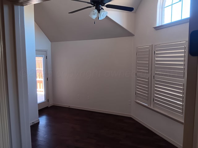 unfurnished room with lofted ceiling, dark wood-type flooring, a ceiling fan, and baseboards