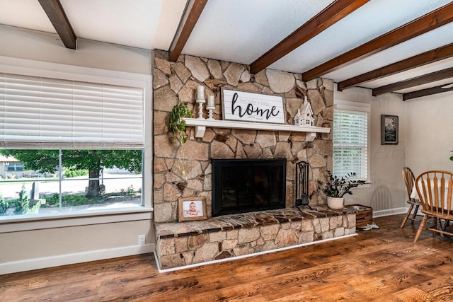 1203 Lee St, Borger, TX 79007 - living area featuring baseboards, beam ceiling, a stone fireplace, and wood finished floors