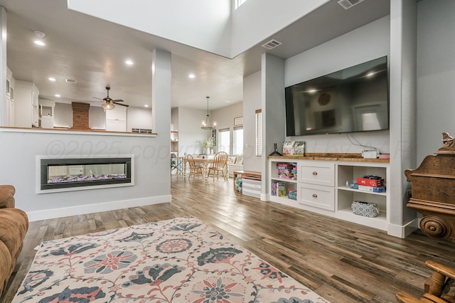 living room featuring ceiling fan, a glass covered fireplace, wood finished floors, and visible vents