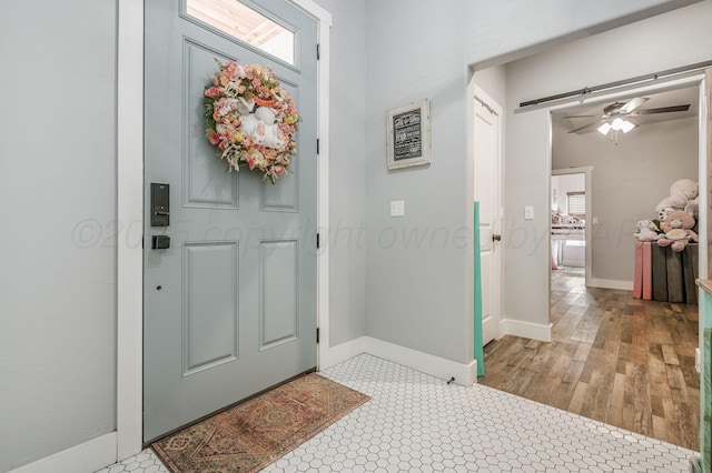 foyer featuring baseboards, wood finished floors, and ceiling fan
