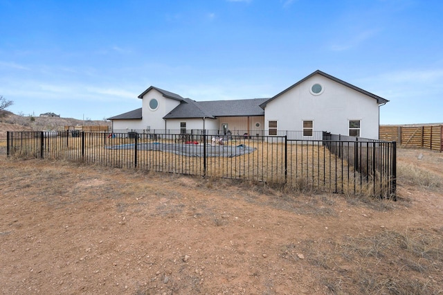 rear view of property featuring stucco siding and fence