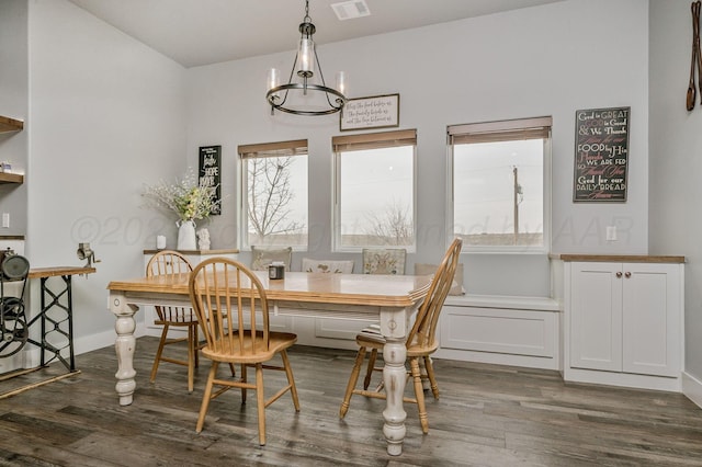 dining space featuring dark wood-type flooring, visible vents, and an inviting chandelier