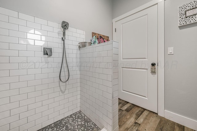 full bathroom featuring wood finished floors and tiled shower