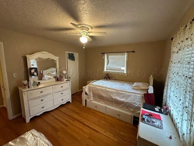 bedroom with hardwood / wood-style flooring, ceiling fan, and a textured ceiling