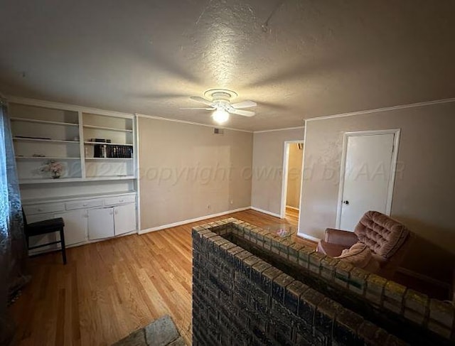 living room with a textured ceiling, light wood-type flooring, ceiling fan, and ornamental molding