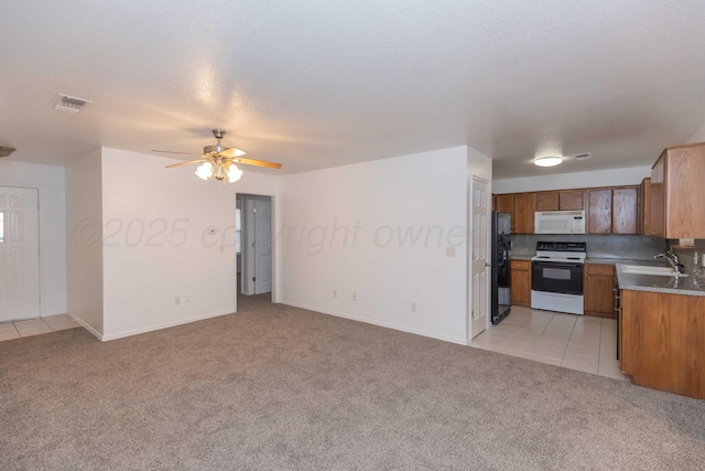 kitchen with light carpet, sink, range with electric cooktop, and black fridge