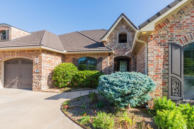 3 Country Club Dr, Amarillo, TX 79124 - property entrance featuring brick siding, a garage, driveway, stone siding, and a tiled roof
