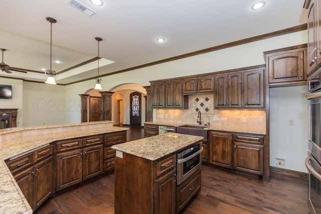 3 Country Club Dr, Amarillo, TX 79124 - kitchen with arched walkways, crown molding, decorative backsplash, stainless steel appliances, and dark brown cabinets