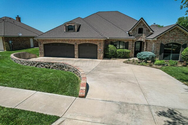 3 Country Club Dr, Amarillo, TX 79124 - french country home with brick siding, an attached garage, driveway, a tile roof, and a front lawn