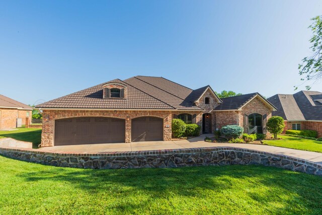 3 Country Club Dr, Amarillo, TX 79124 - french country inspired facade with a tiled roof, an attached garage, brick siding, a front yard, and concrete driveway
