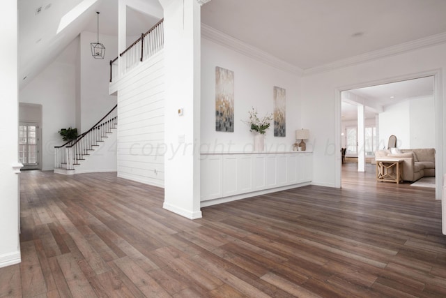 unfurnished living room with ornamental molding, a towering ceiling, and dark hardwood / wood-style flooring