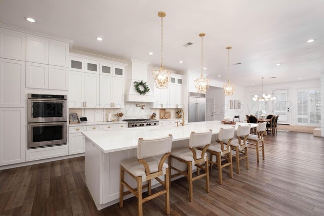 kitchen featuring a spacious island, dark hardwood / wood-style flooring, hanging light fixtures, and appliances with stainless steel finishes