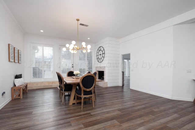 dining space featuring a large fireplace, dark hardwood / wood-style flooring, a notable chandelier, and crown molding