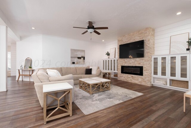 living room with dark hardwood / wood-style flooring, a stone fireplace, and ceiling fan