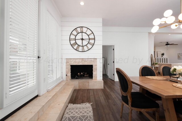 dining space featuring a stone fireplace, hardwood / wood-style floors, and ceiling fan