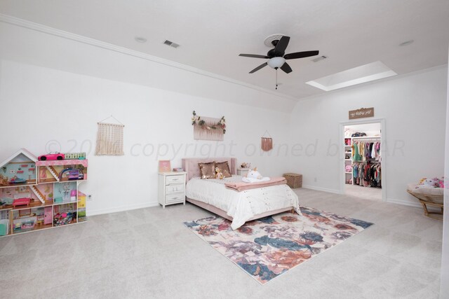 bedroom featuring light colored carpet, ornamental molding, ceiling fan, a closet, and a walk in closet