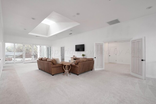 carpeted living room with french doors, a skylight, and a tray ceiling