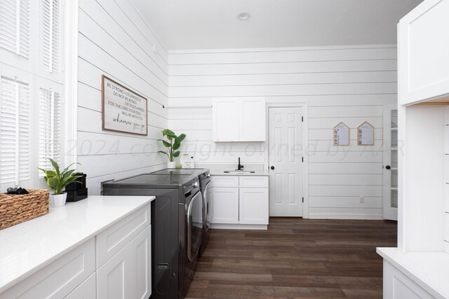 laundry area with dark hardwood / wood-style flooring, cabinets, wood walls, sink, and washer and clothes dryer