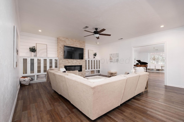 living room featuring a fireplace, ceiling fan, crown molding, and dark hardwood / wood-style flooring